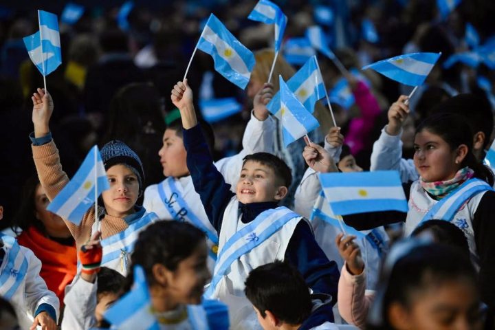 Niños con guardapolvo flameando banderas Argentinas