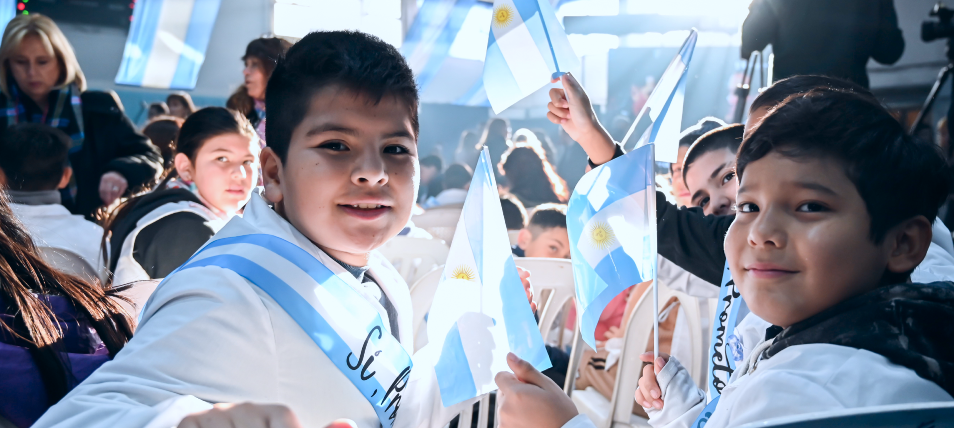 Estudiantes de escuelas bonaerenses festejando el 25 de mayo con banderas argentinas.